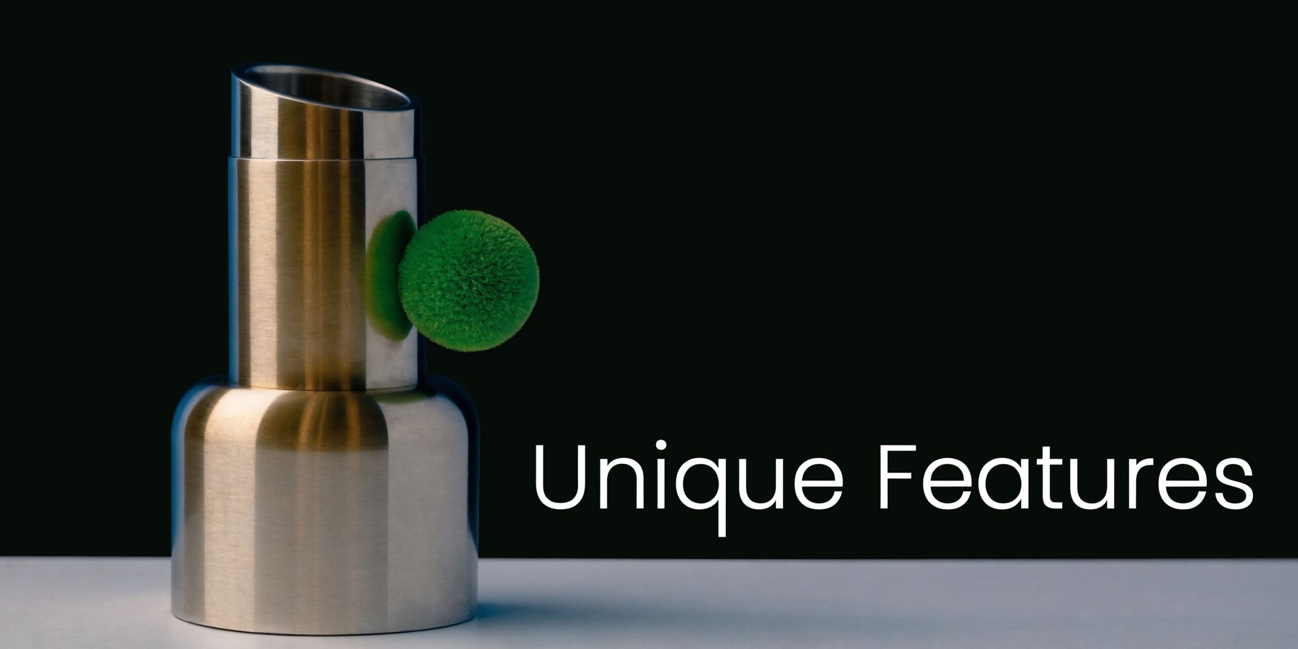 A modern metallic cylindrical object with a fuzzy green circular handle sitting on a white table.
