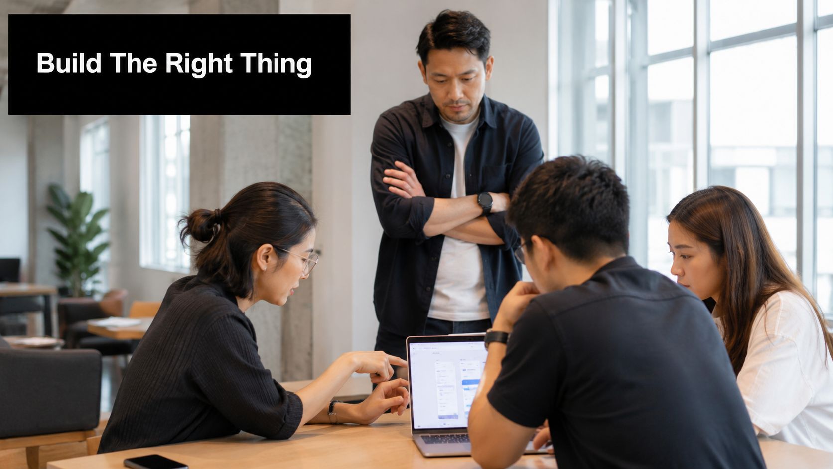 A diverse team of professionals collaborating around a laptop to discuss product validation and design strategies.